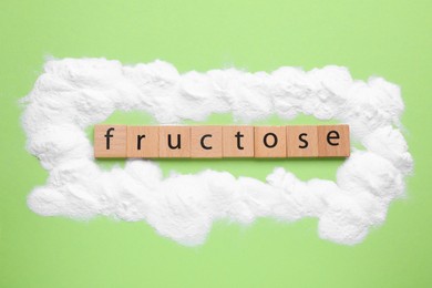 Photo of Word Fructose made of wooden cubes and powder on light green background, flat lay
