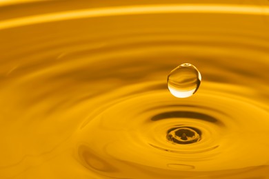 Splash of golden oily liquid with drop as background, closeup. Space for text