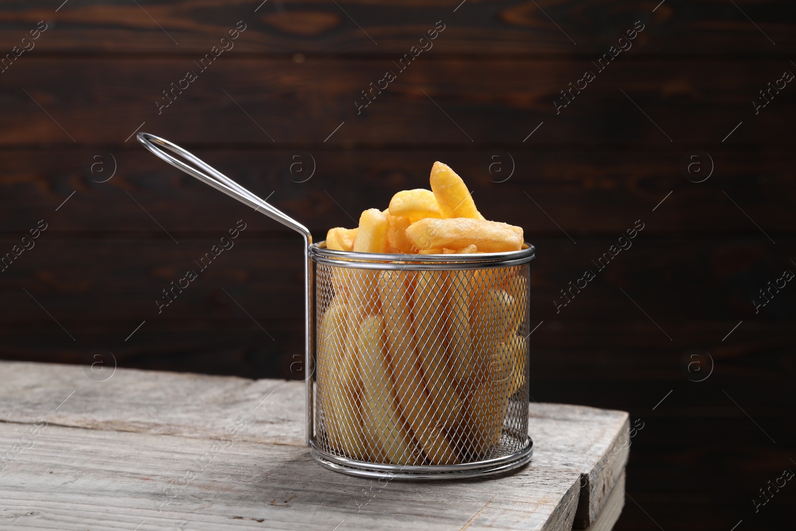 Photo of Metal basket with tasty French fries on light grey wooden table