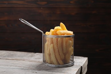 Photo of Metal basket with tasty French fries on light grey wooden table
