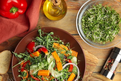 Photo of Delicious vegetable salad with microgreen served on wooden table, flat lay