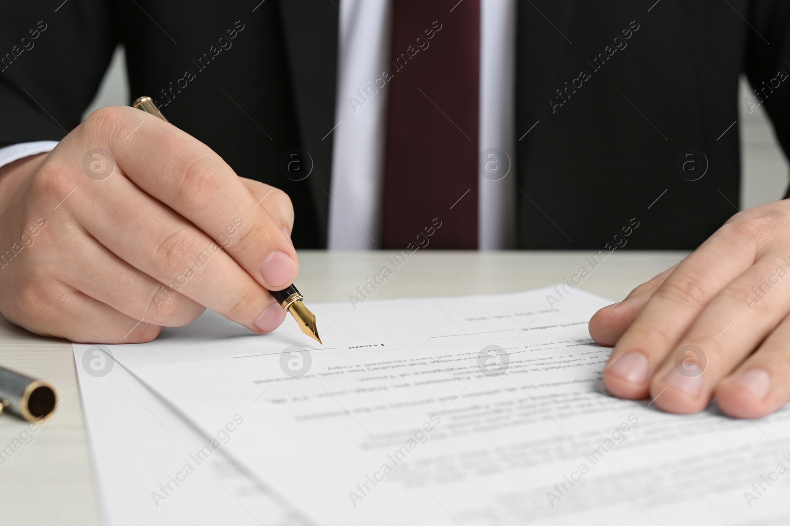 Photo of Notary signing document at wooden table, closeup