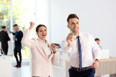 Photo of Happy young employees with dart in office