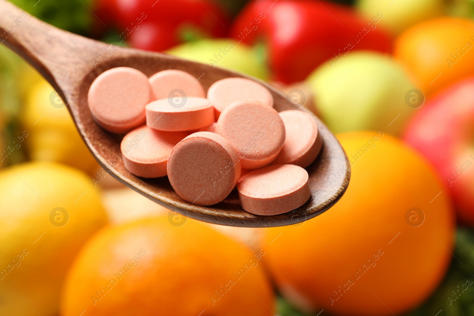 Photo of Dietary supplements in wooden spoon near products, closeup