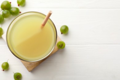 Photo of Tasty gooseberry juice on white wooden table, flat lay. Space for text