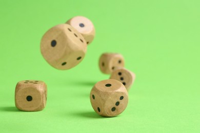 Photo of Many wooden game dices falling on green background, closeup. Space for text