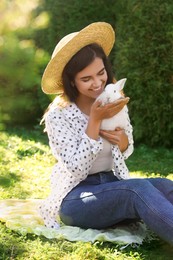Photo of Happy woman with cute rabbit on green grass outdoors