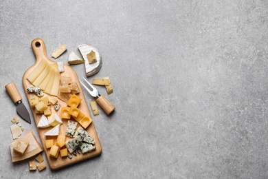 Photo of Cheese plate and cutlery on grey table, flat lay. Space for text