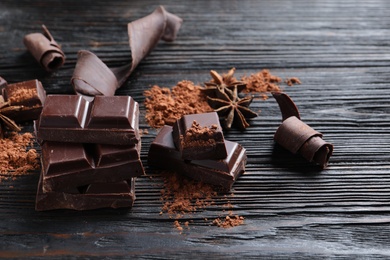 Photo of Pieces of black chocolate on wooden table