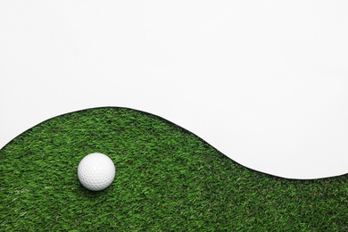 Photo of Golf ball and white paper on green artificial grass, top view with space for text
