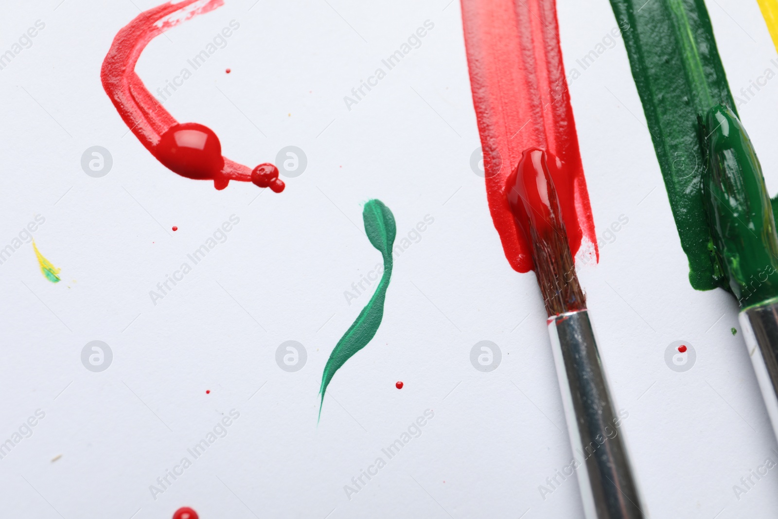 Photo of Brushes with different paints and strokes on white background, flat lay