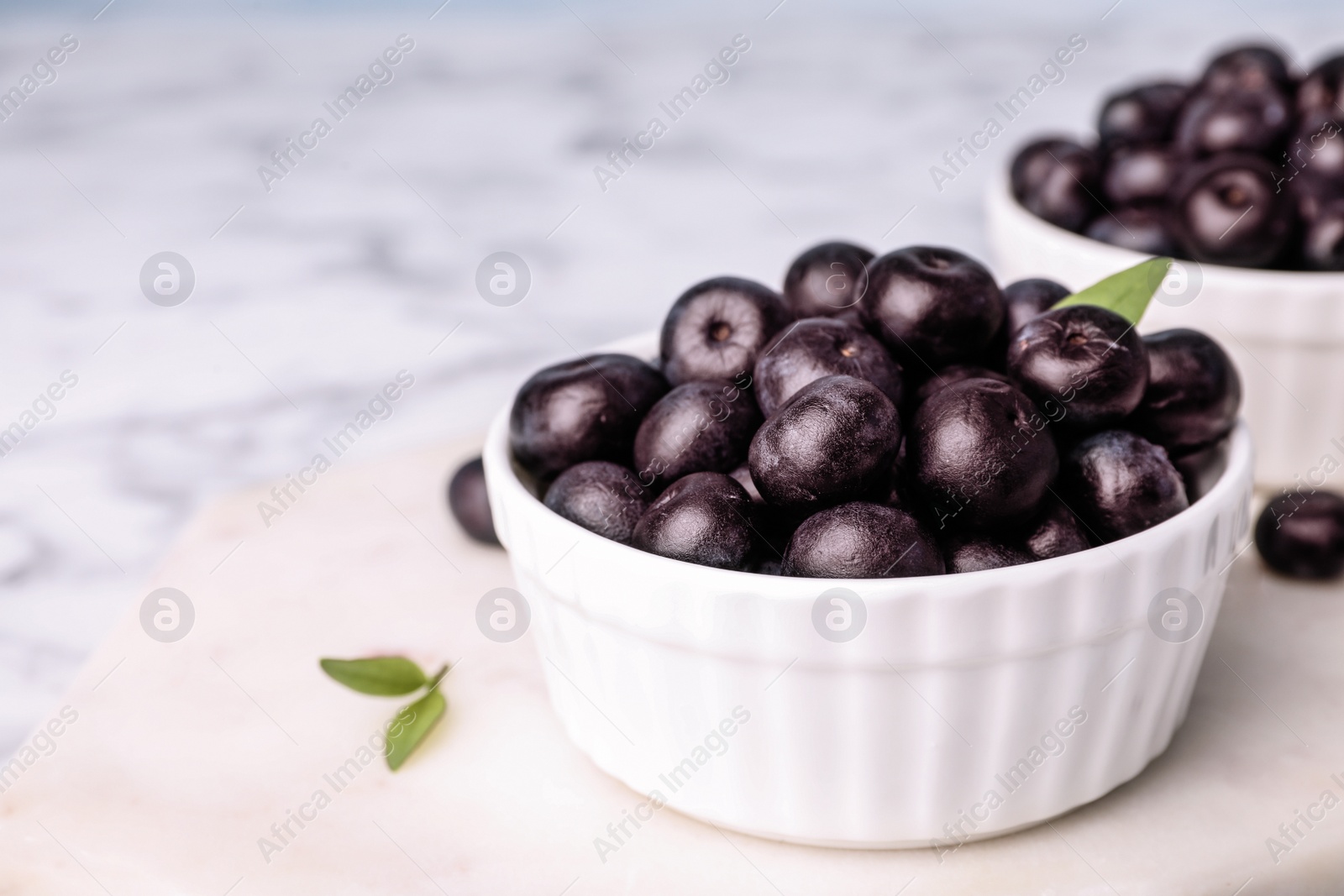 Photo of Bowl of fresh acai berries on board, closeup. Space for text