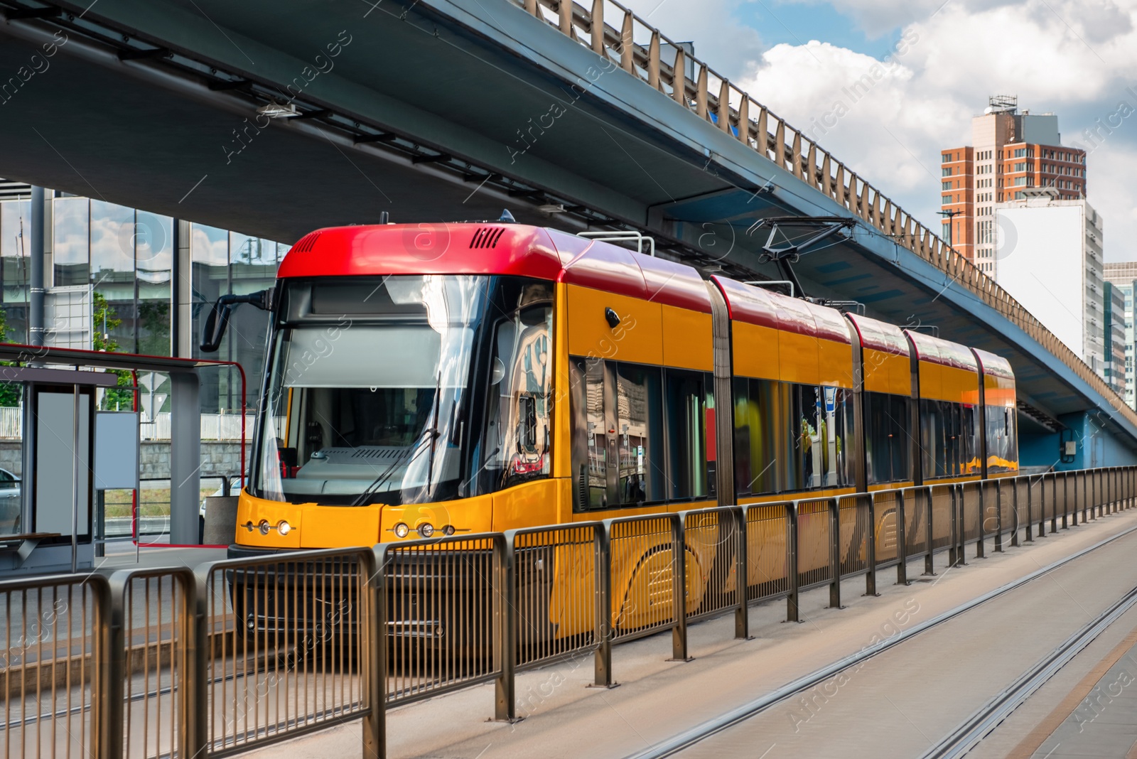 Photo of Modern streetcar near tram stop on sunny day. Public transport