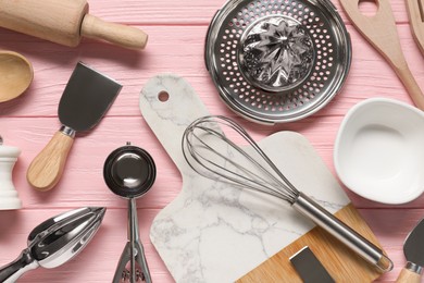 Photo of Set of different kitchen utensils on pink wooden table, flat lay