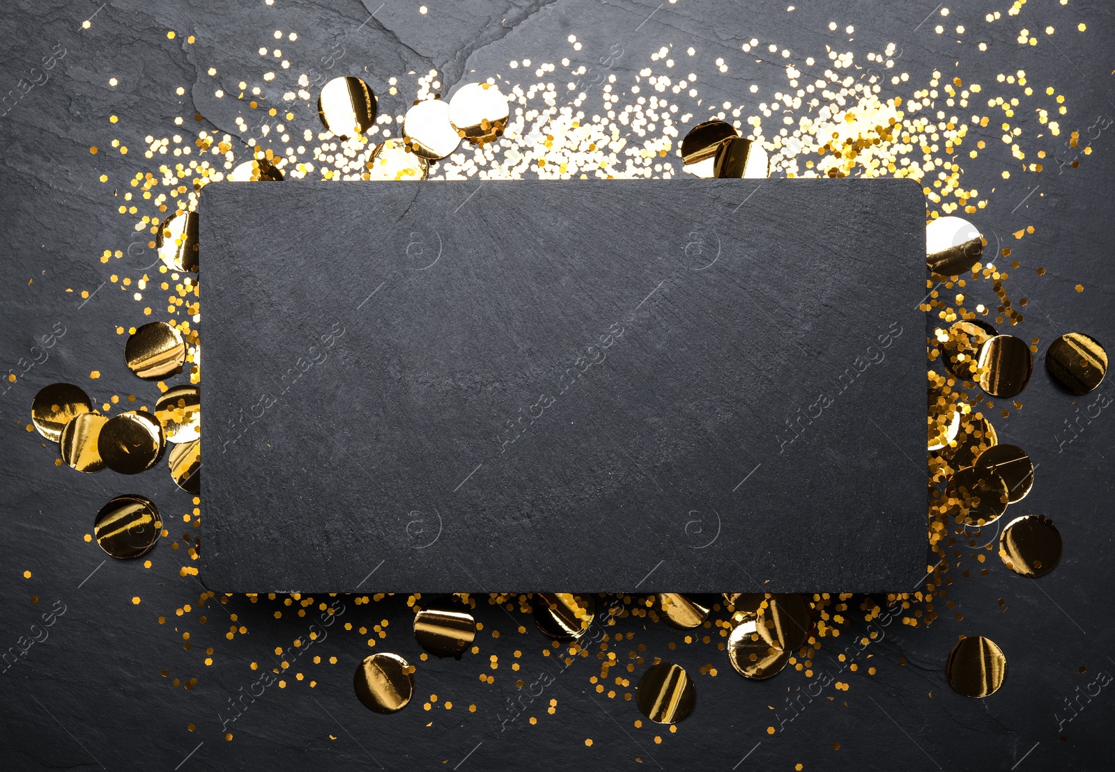 Photo of Slate board and confetti on black background, top view. Space for text