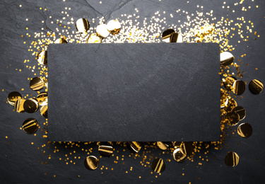 Photo of Slate board and confetti on black background, top view. Space for text