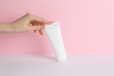 Photo of Woman with tube of cream on color background, closeup