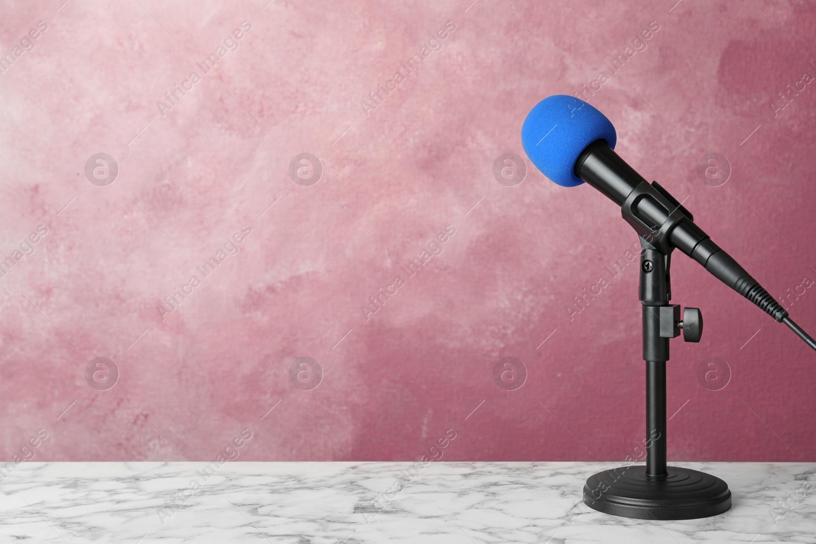 Photo of Microphone on table against color background. Space for text