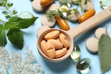 Photo of Different pills and herbs on light blue background, closeup. Dietary supplements