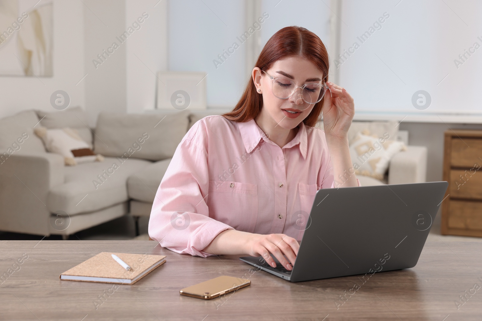 Photo of Beautiful woman using laptop at wooden table in room