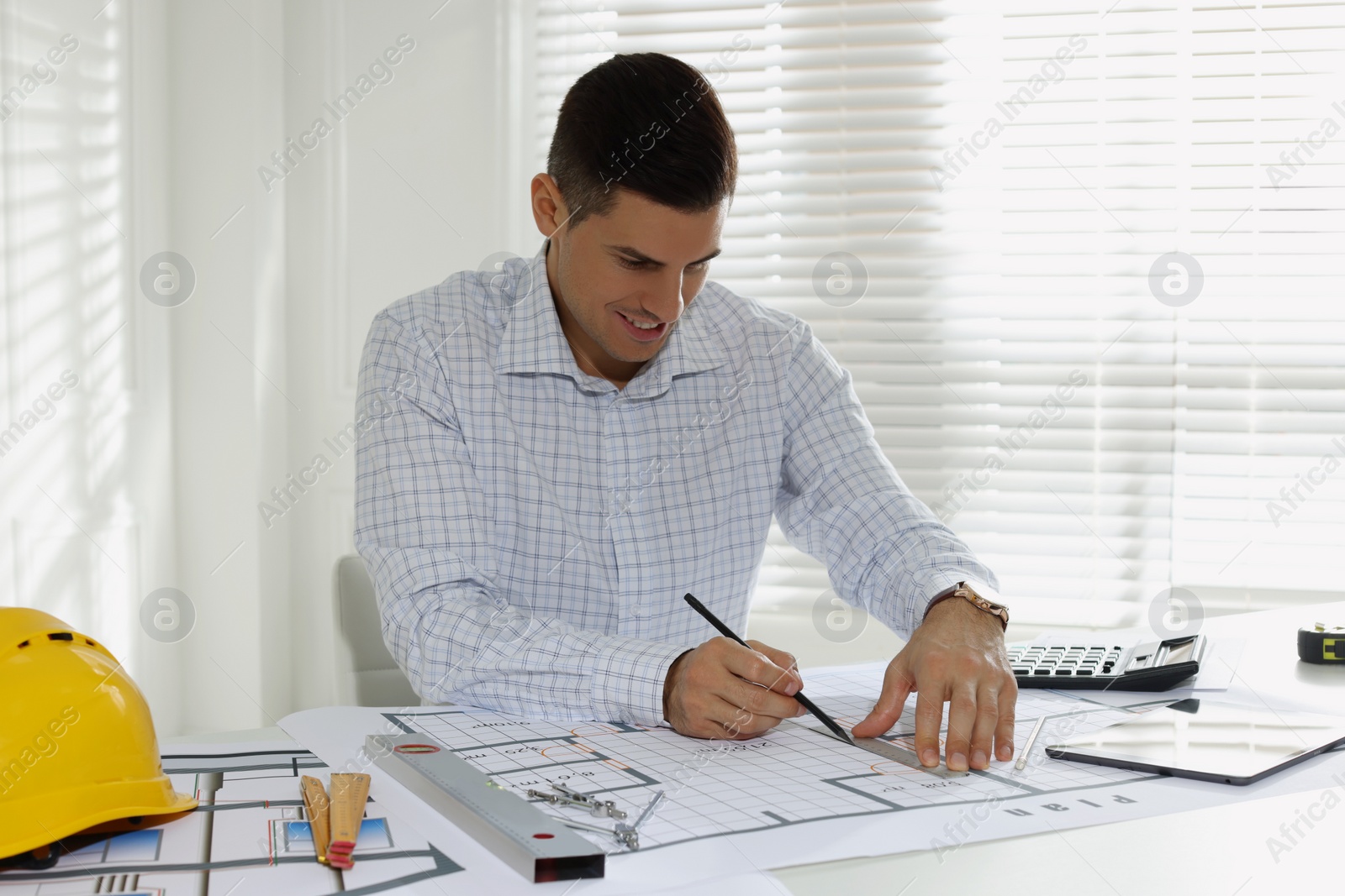 Photo of Architect working with construction drawings in office