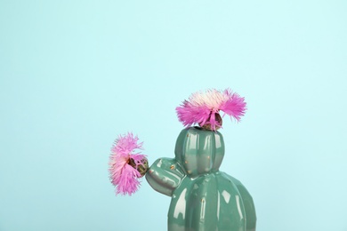 Photo of Trendy cactus shaped ceramic vase with flowers on color background