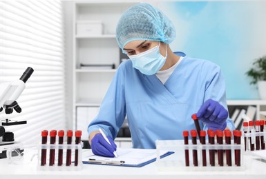 Laboratory testing. Doctor with blood samples in tubes at white table indoors