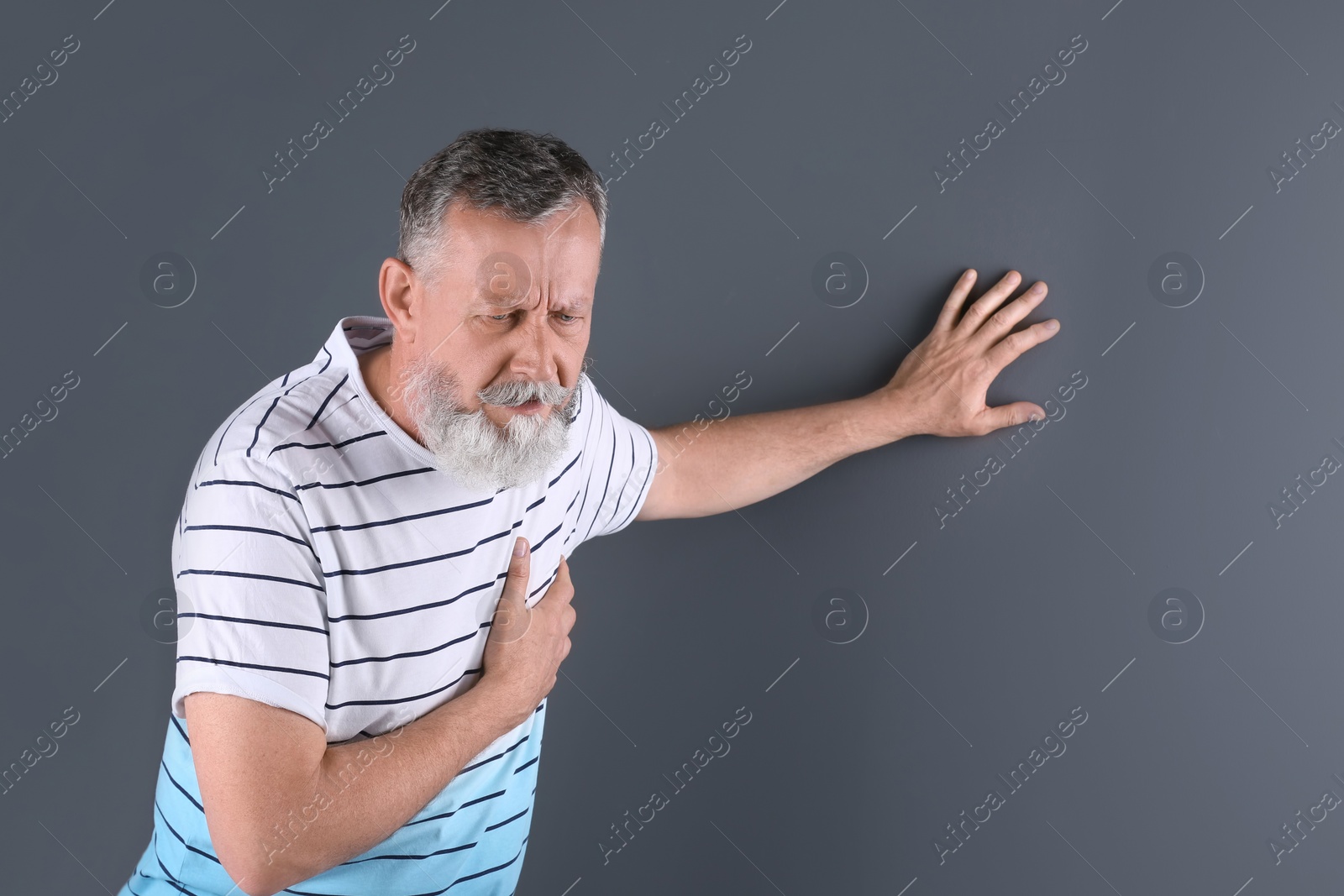 Photo of Mature man having heart attack on gray background