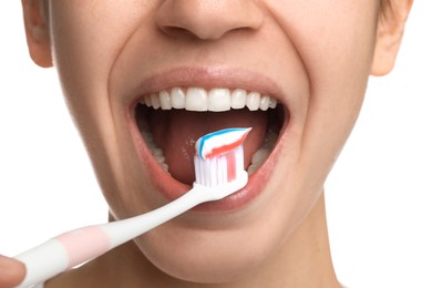 Woman brushing teeth with paste on white background, closeup. Dental care