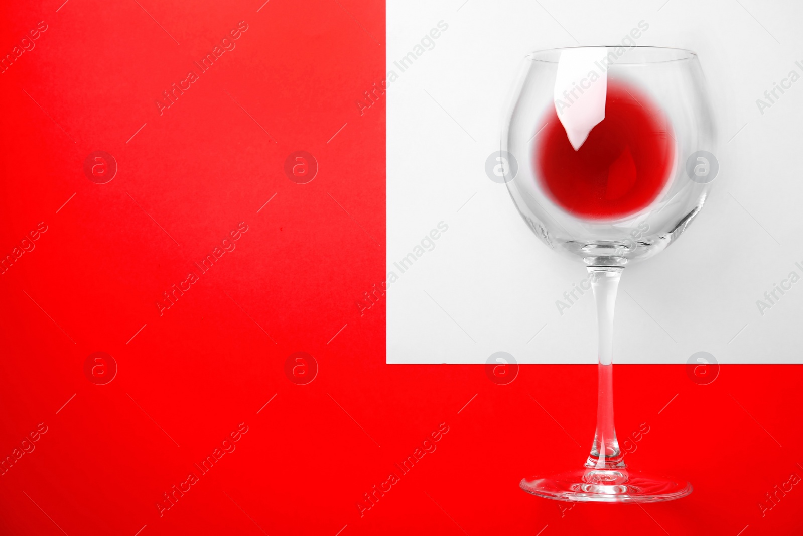 Photo of Glass with wine made of fresh ripe juicy grapes and space for text on color background, top view