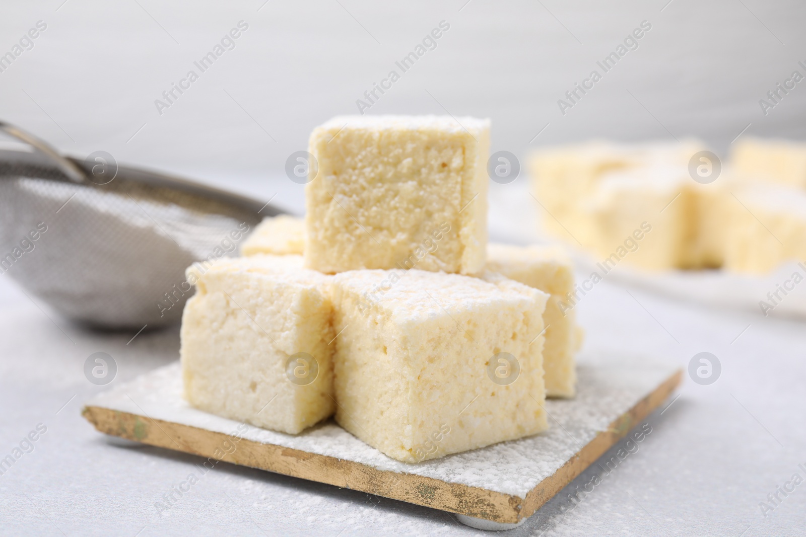 Photo of Delicious sweet marshmallows with powdered sugar on light grey table, closeup