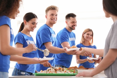 Volunteers serving food to poor people indoors