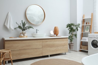 Modern bathroom interior with stylish mirror, eucalyptus branches and vessel sink