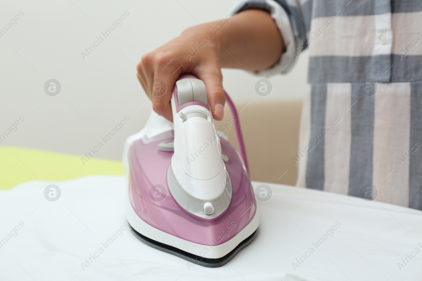 Photo of Young woman ironing clean shirt at home, closeup. Laundry day