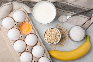 Different ingredients for cooking tasty oatmeal pancakes on grey table, flat lay