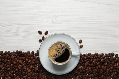 Photo of Cup of aromatic hot coffee and beans on white wooden table, flat lay. Space for text