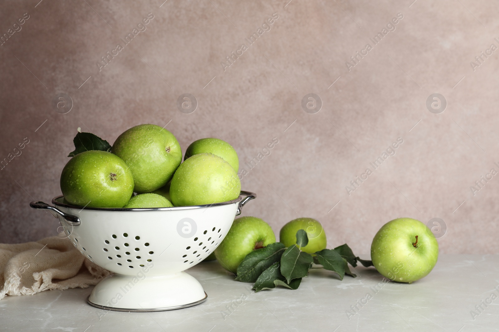 Photo of Composition with juicy green apples in colander on table. Space for text