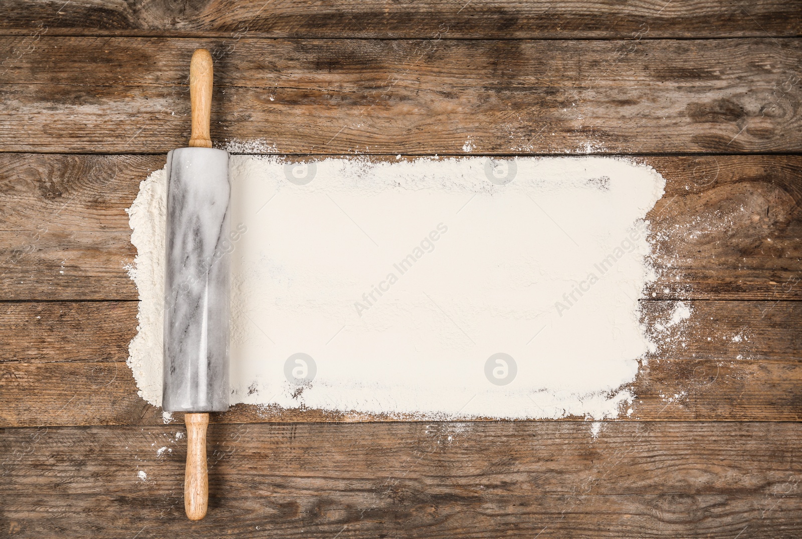 Photo of Flour and rolling pin on wooden table, flat lay
