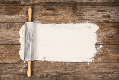 Flour and rolling pin on wooden table, flat lay