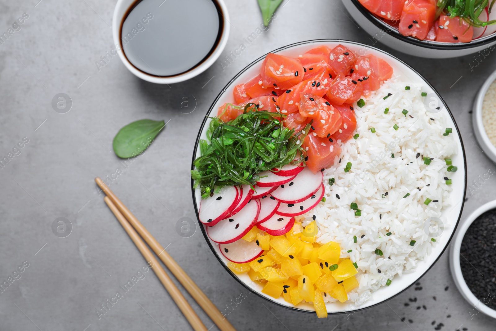 Photo of Delicious poke bowl with salmon and vegetables served on light grey table, flat lay