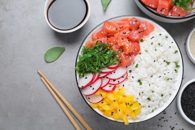 Photo of Delicious poke bowl with salmon and vegetables served on light grey table, flat lay