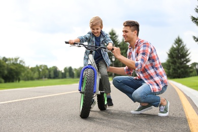 Dad teaching son to ride bicycle outdoors