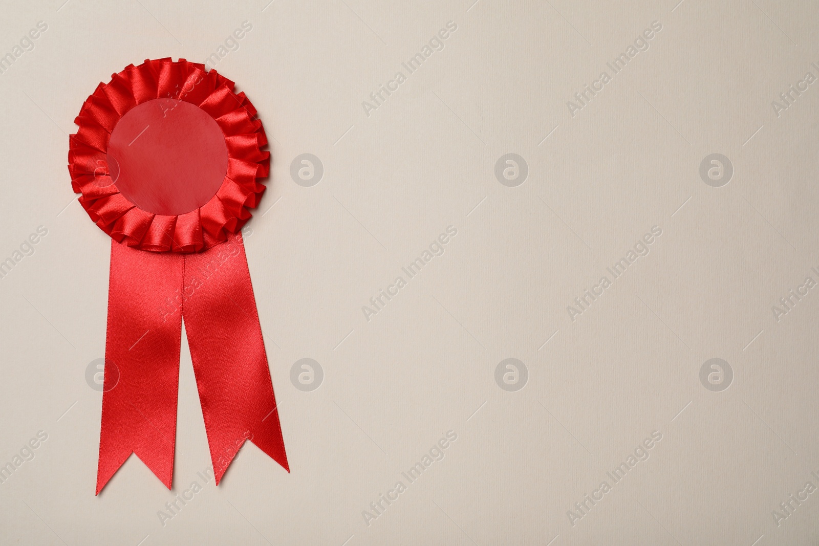 Photo of Red award ribbon on beige background, top view. Space for text