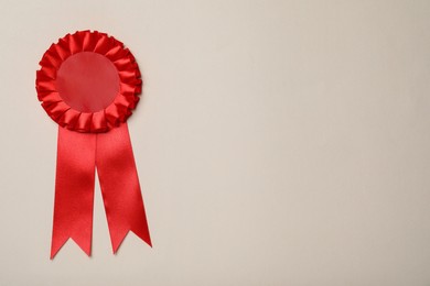 Photo of Red award ribbon on beige background, top view. Space for text