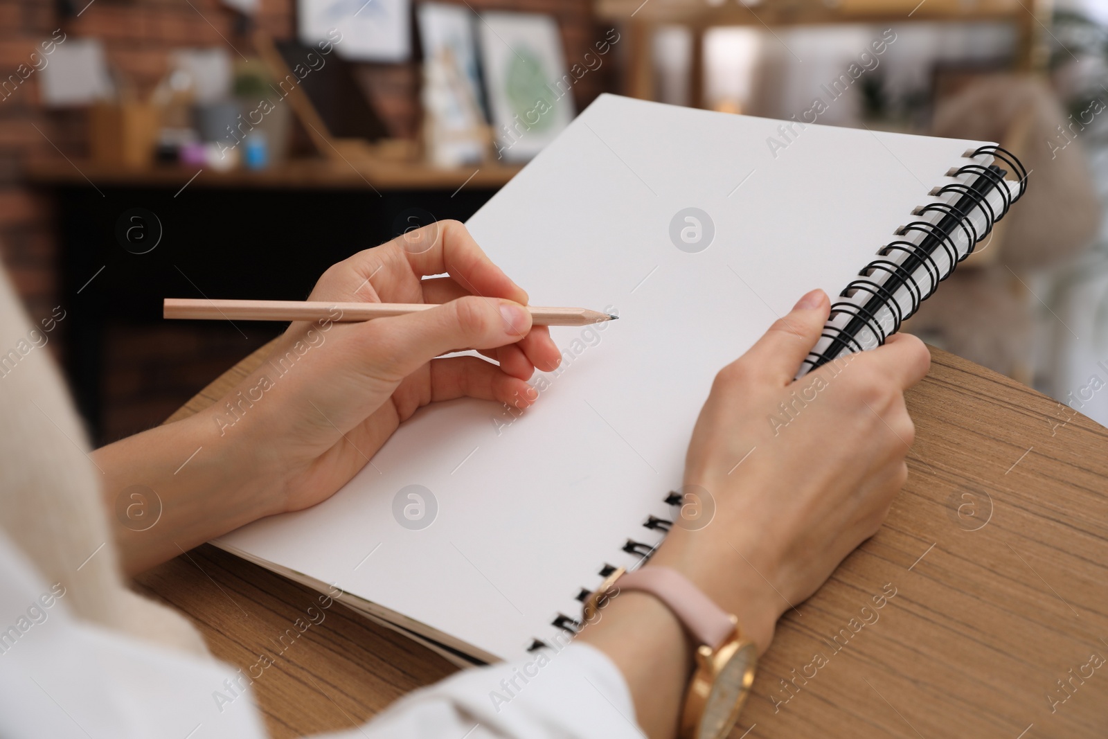 Photo of Woman drawing in sketchbook with pencil at home, closeup