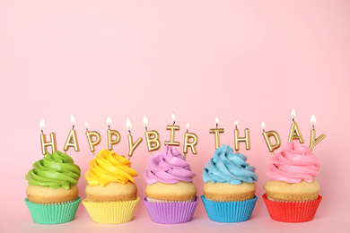 Photo of Birthday cupcakes with burning candles on pink background. Space for text