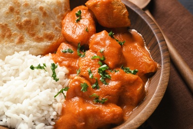 Delicious butter chicken with rice and naan in bowl on table, closeup