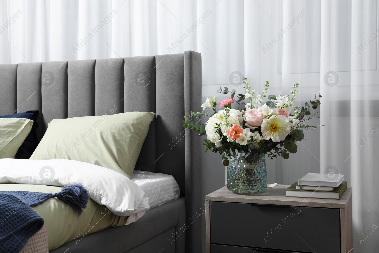 Photo of Bouquet of beautiful flowers on bedside table indoors