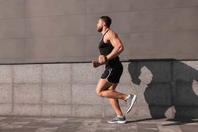 Photo of Young man running near building outdoors. Space for text