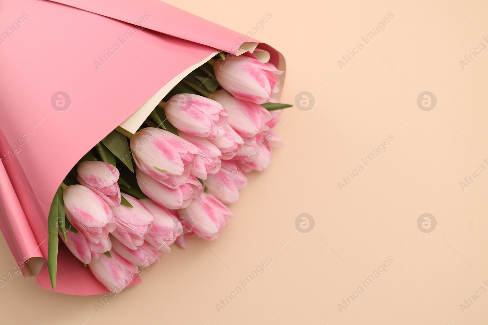 Photo of Beautiful bouquet of fresh pink tulips on beige background. Space for text